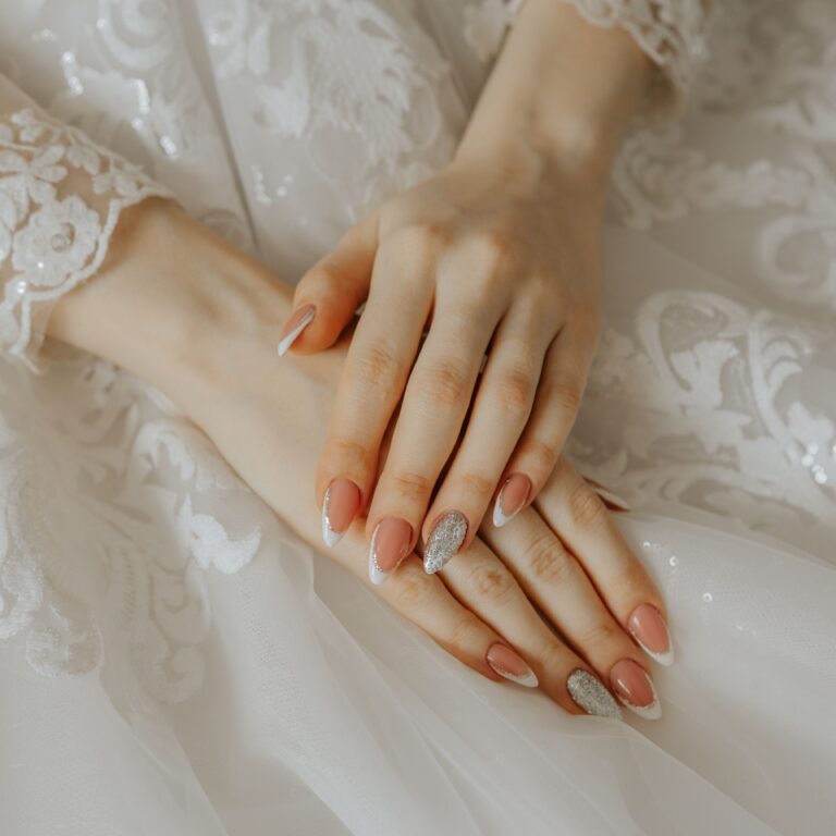 Close-up of a bride's hands on a detailed lace wedding dress, highlighting elegance and beauty.